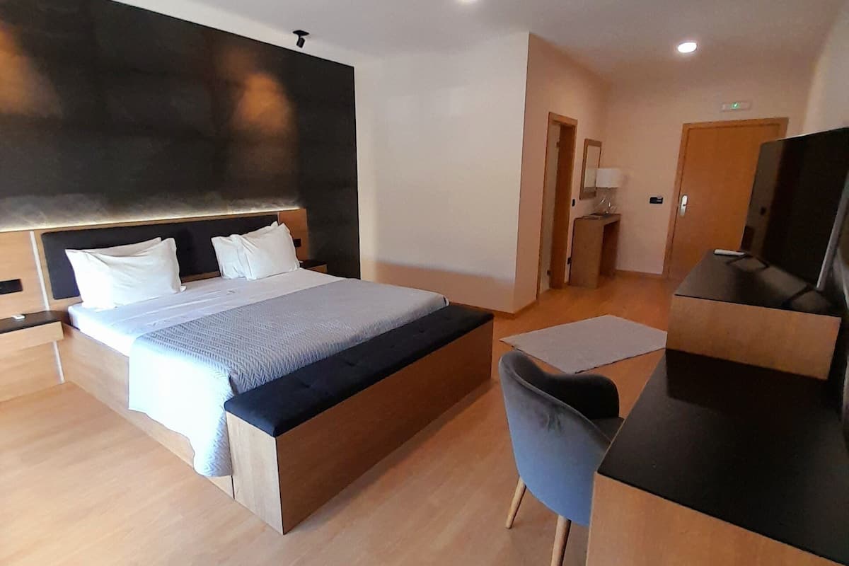 A modern hotel room with a large bed, a desk, and a chair.