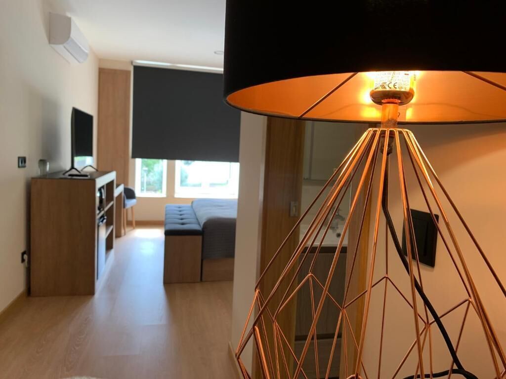 Una sala de estar moderna con una lámpara de pie geométrica, un televisor de pantalla plana y un sofá.
