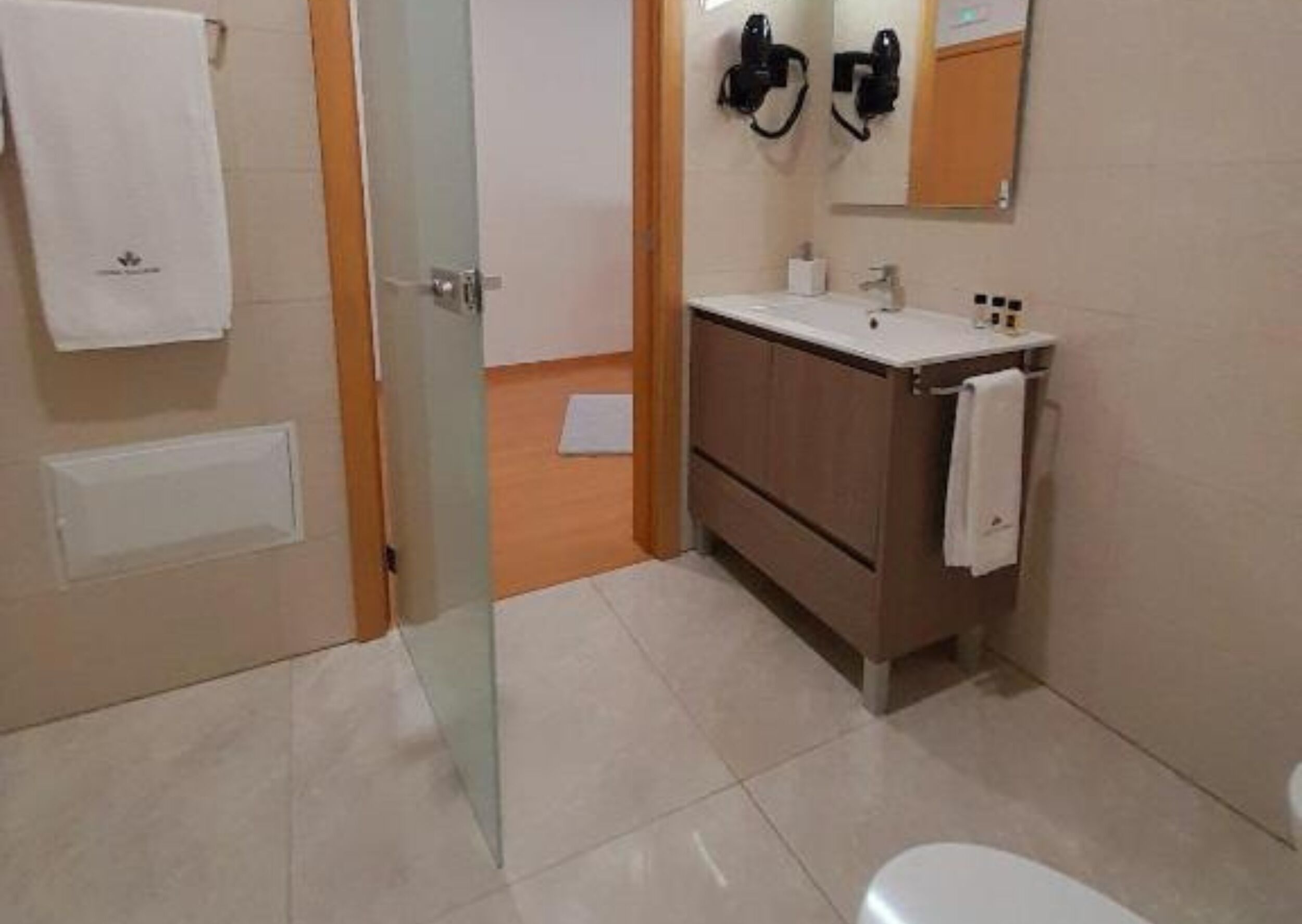 A bathroom with a toilet, a sink, a mirror, and a towel rack.