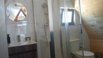 A bathroom with a glass-enclosed shower, a wooden ceiling, a sink with toiletries, and a toilet.