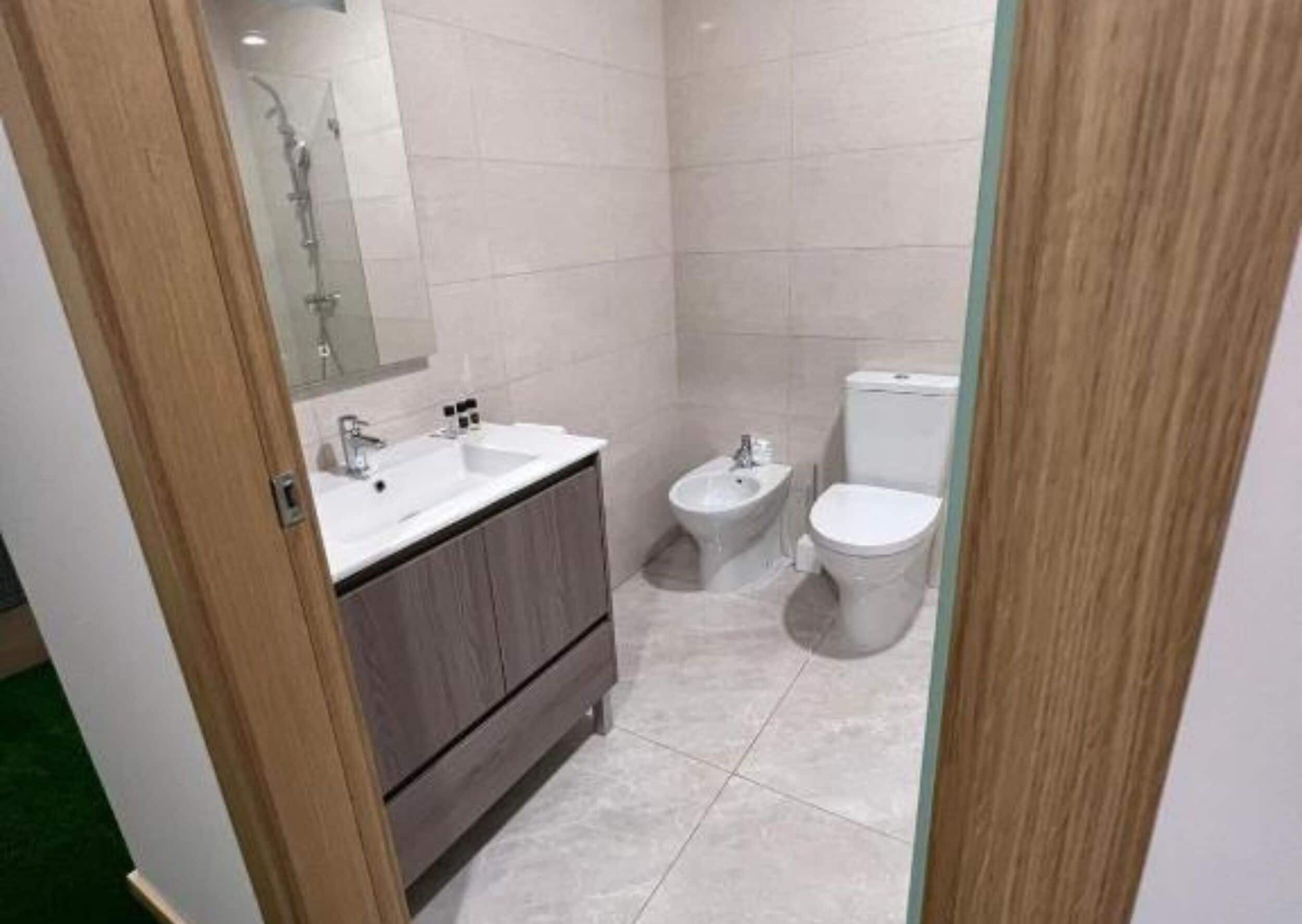 A small bathroom with a sink, bidet, and toilet.