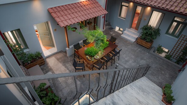 Un patio con zona de comedor, plantas en macetas y una escalera.