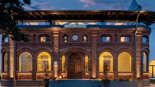 The exterior of the Mercure Hotel with a brick facade, arched windows, and a covered entrance. - Mercure Conacul Cozieni (Ganeasa)
