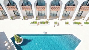 A rooftop pool with a clear blue water surface, surrounded by white columns and multiple seating areas with chairs and tables. - Mercure Conacul Cozieni (Ganeasa)