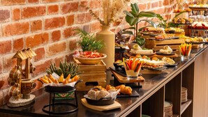 A buffet with various food items, a brick wall, and decorative plants. - Mercure Conacul Cozieni (Ganeasa)