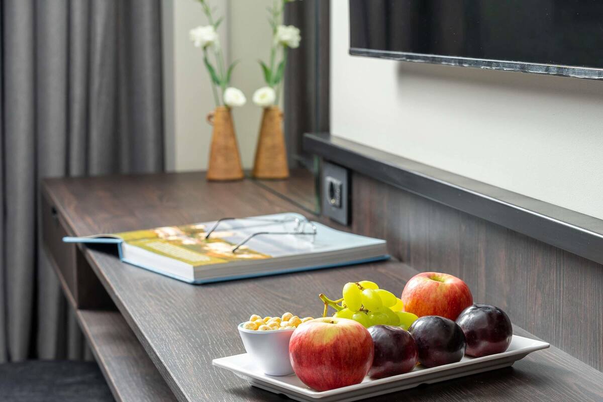 Una mesa de madera con un plato de frutas, un tazón de cereal y un libro.
