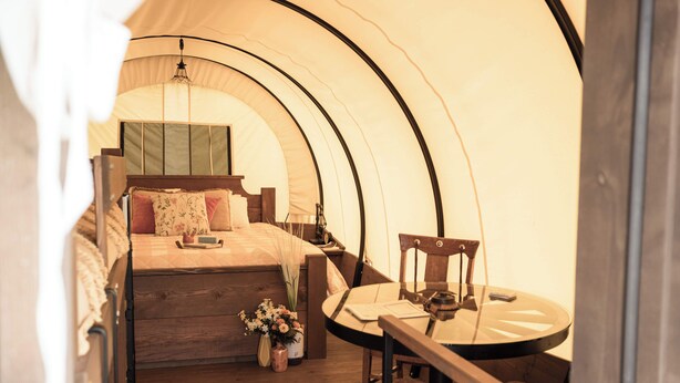 A tented room with a bed, a table, and a chair.