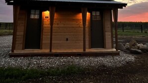 A wooden cabin with a metal roof, two doors, and a small porch area.
