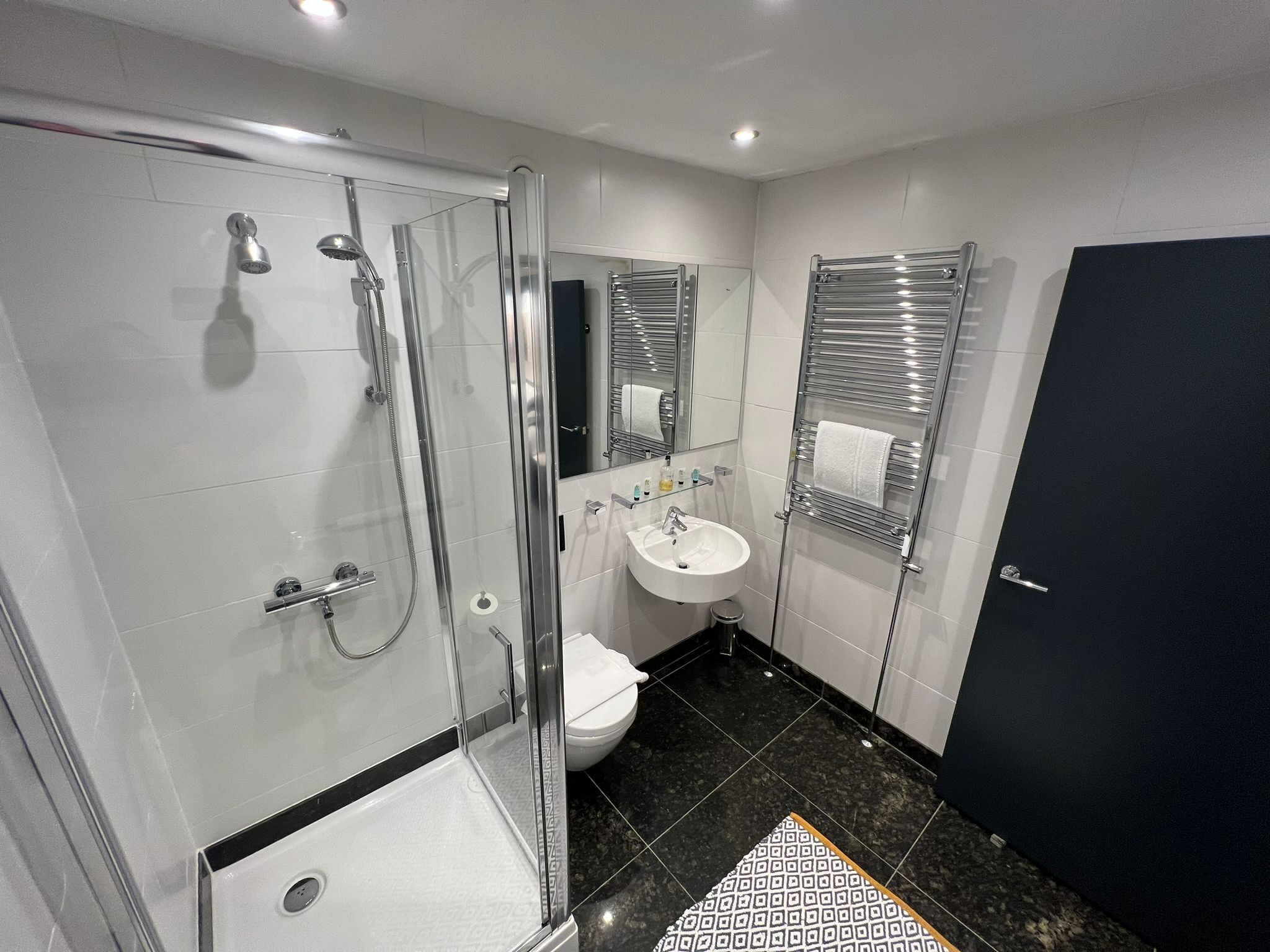 A modern bathroom with a glass-enclosed shower, a white sink, and a toilet.