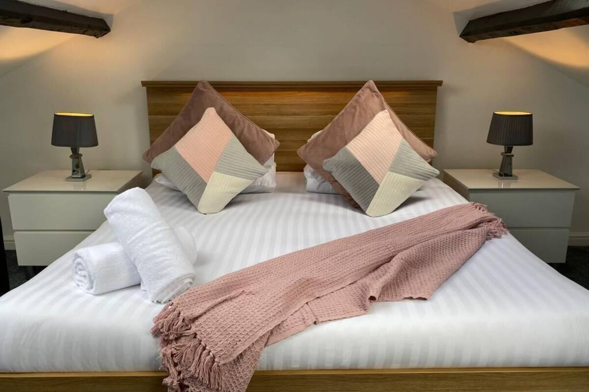 A neatly made bed with pillows, a blanket, and a lamp on a bedside table.