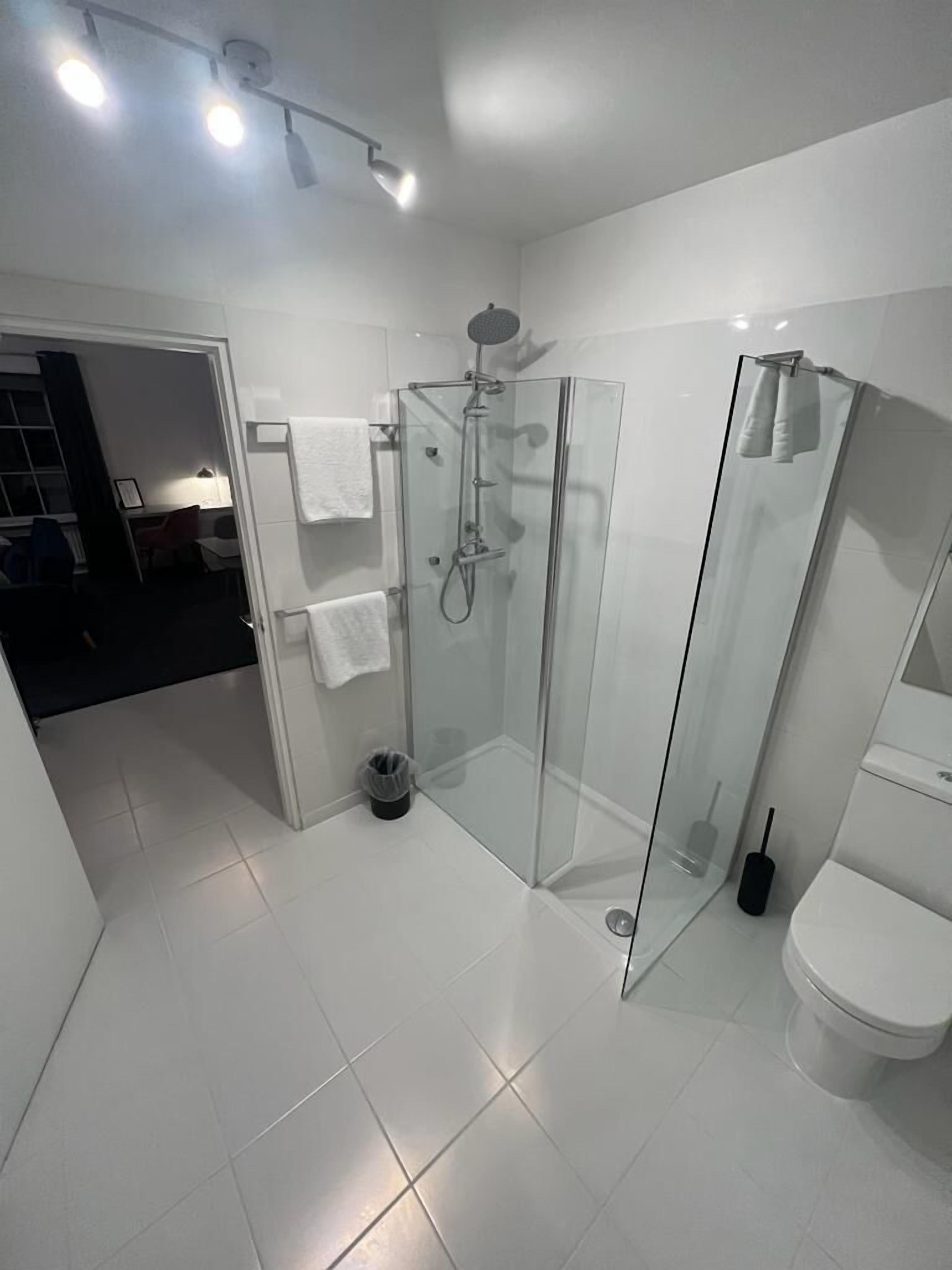 A modern bathroom with a glass-enclosed shower, a toilet, and a sink.