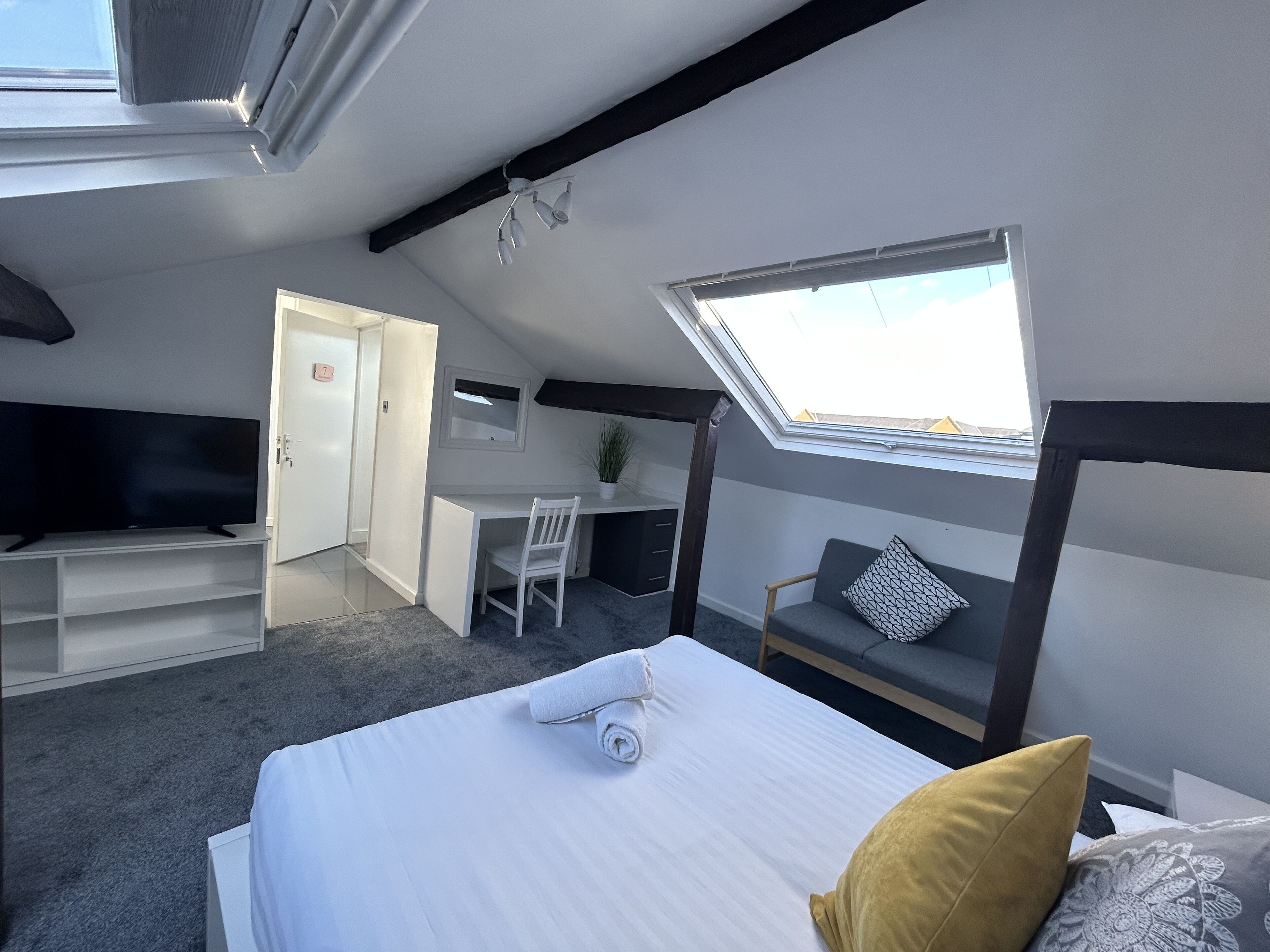 Une chambre moderne et compacte, équipée d’un lit, d’un bureau et d’un coin salon.