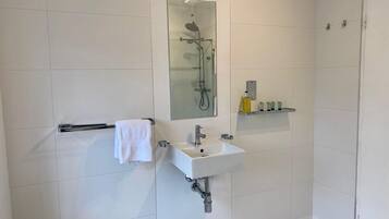 Ein modernes Badezimmer mit einer gläsernen Duschkabine, einem weißen Waschbecken und einem Handtuchhalter.