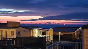 Una hilera de cabañas frente a la playa con vista al atardecer sobre el océano.