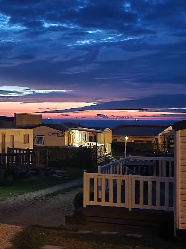 A row of beachside cabins with a view of the sunset over the ocean.