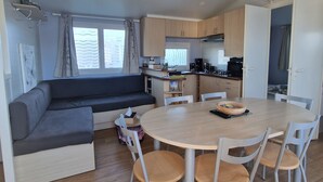Un espacio habitable compacto con sofá, mesa de comedor, sillas y kitchenette.