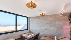 Un moderno spa con dos camillas de masaje curvas, un ventanal con vistas y una pared con textura.