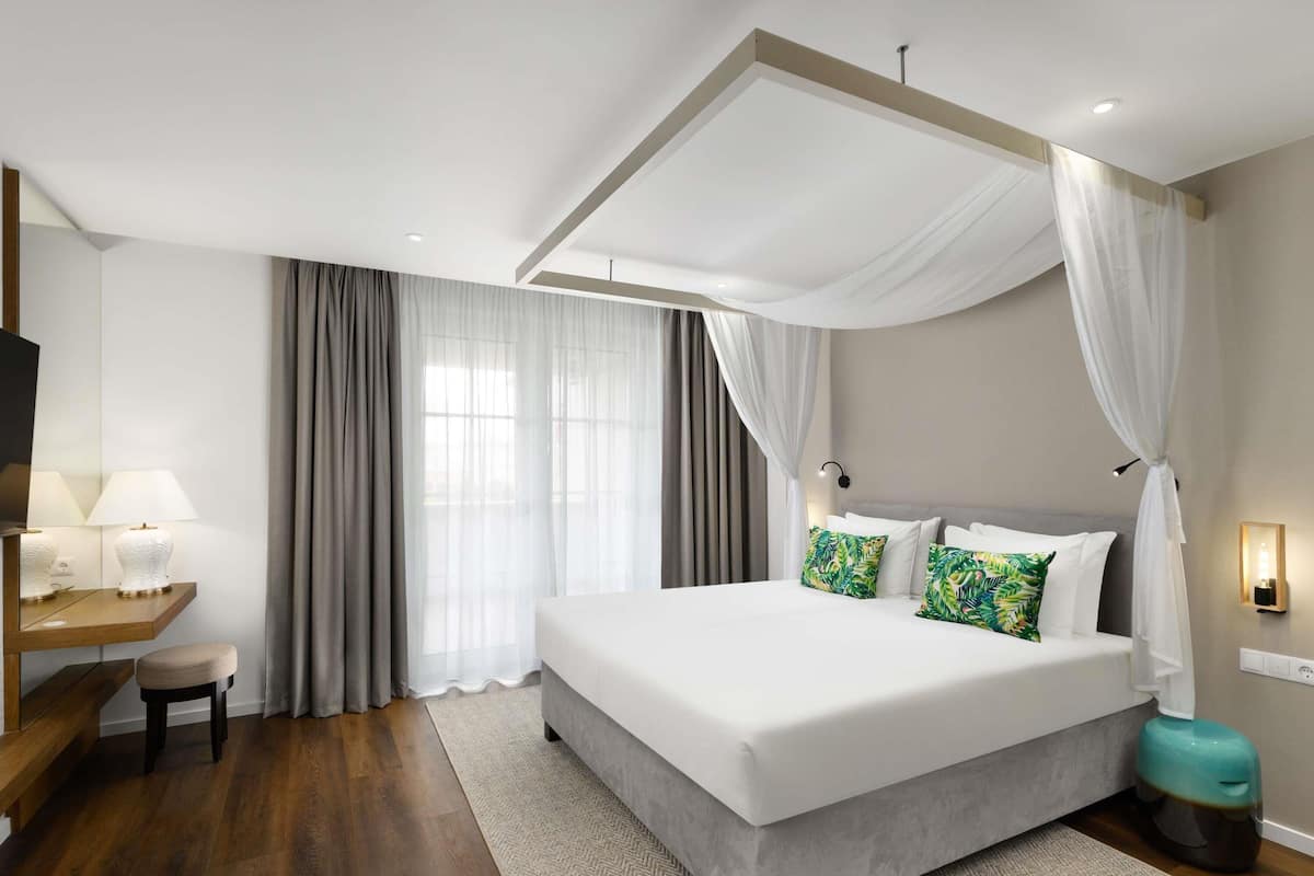 Una habitación de hotel moderna con una cama grande, un escritorio con lámpara y una televisión.