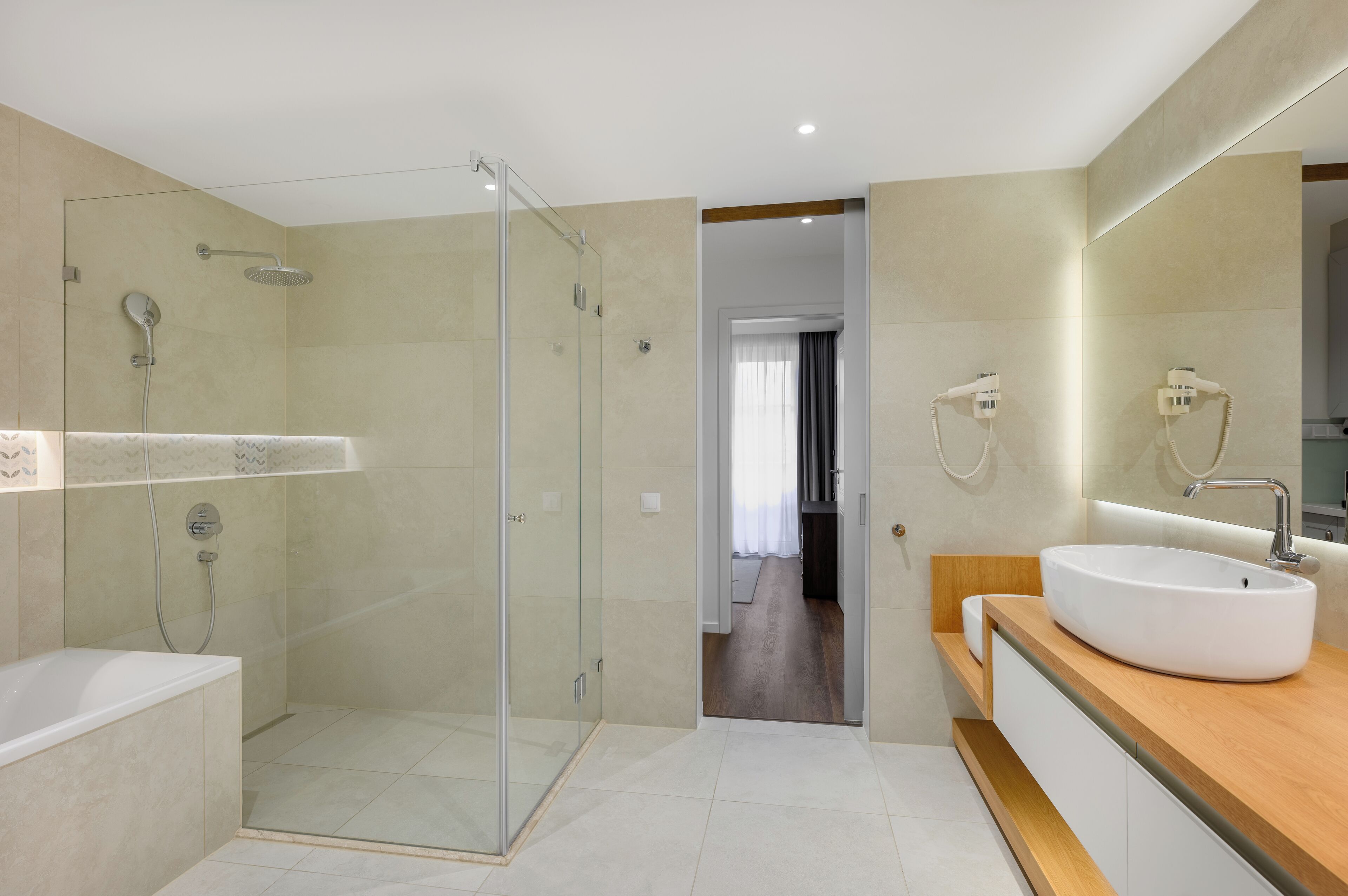 Ein modernes Badezimmer mit einer gläsernen Duschkabine, einem großzügigen Waschbecken und einer begehbaren Dusche.