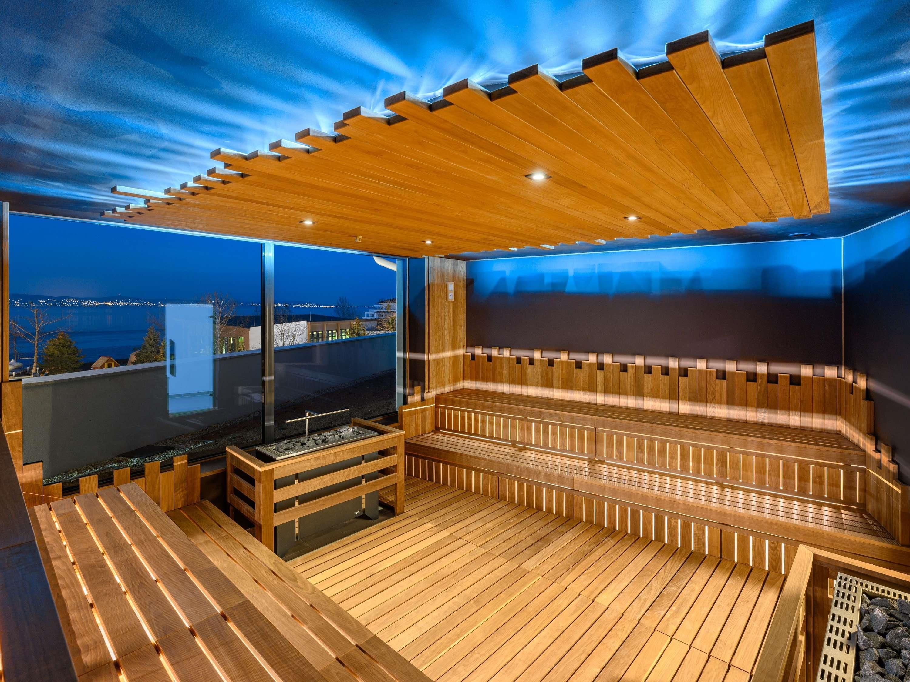 Una sauna moderna con bancos de madera y un muro de cristal que ofrece vistas a la ciudad.