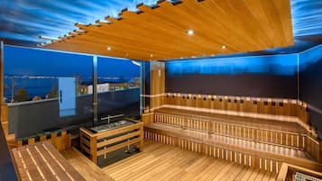 Una sauna moderna con bancos de madera y un muro de cristal que ofrece vistas a la ciudad.