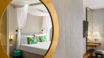 A hotel room with a bed, a nightstand, a mirror, and a small stool.