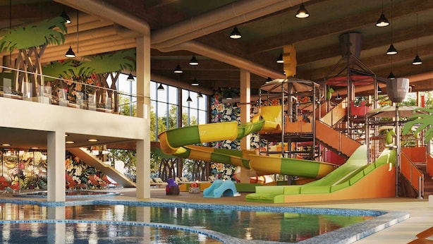 Parque acuático interior con una piscina grande, toboganes y una zona de juegos.