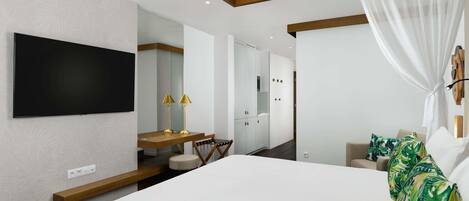 Una habitación de hotel moderna con una cama grande, un televisor de pantalla plana montado en la pared, un escritorio de madera con una silla y un espejo amplio.