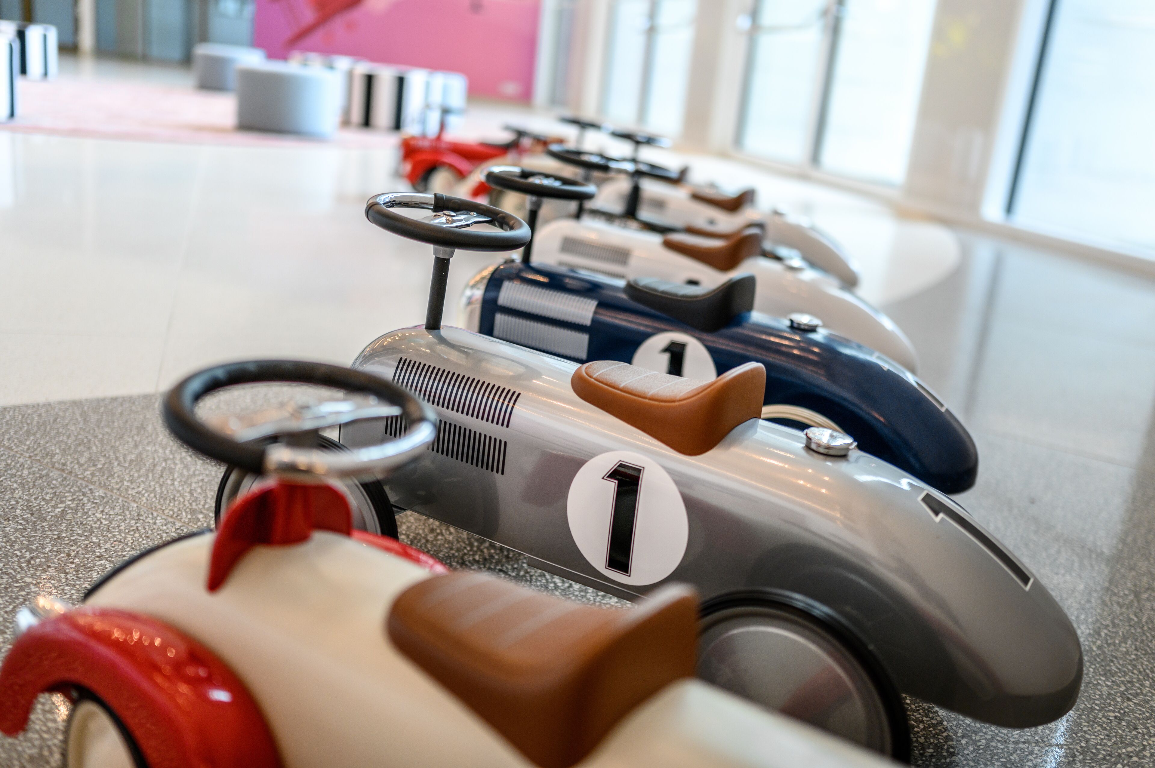 A row of vintage toy cars in a brightly lit indoor space.