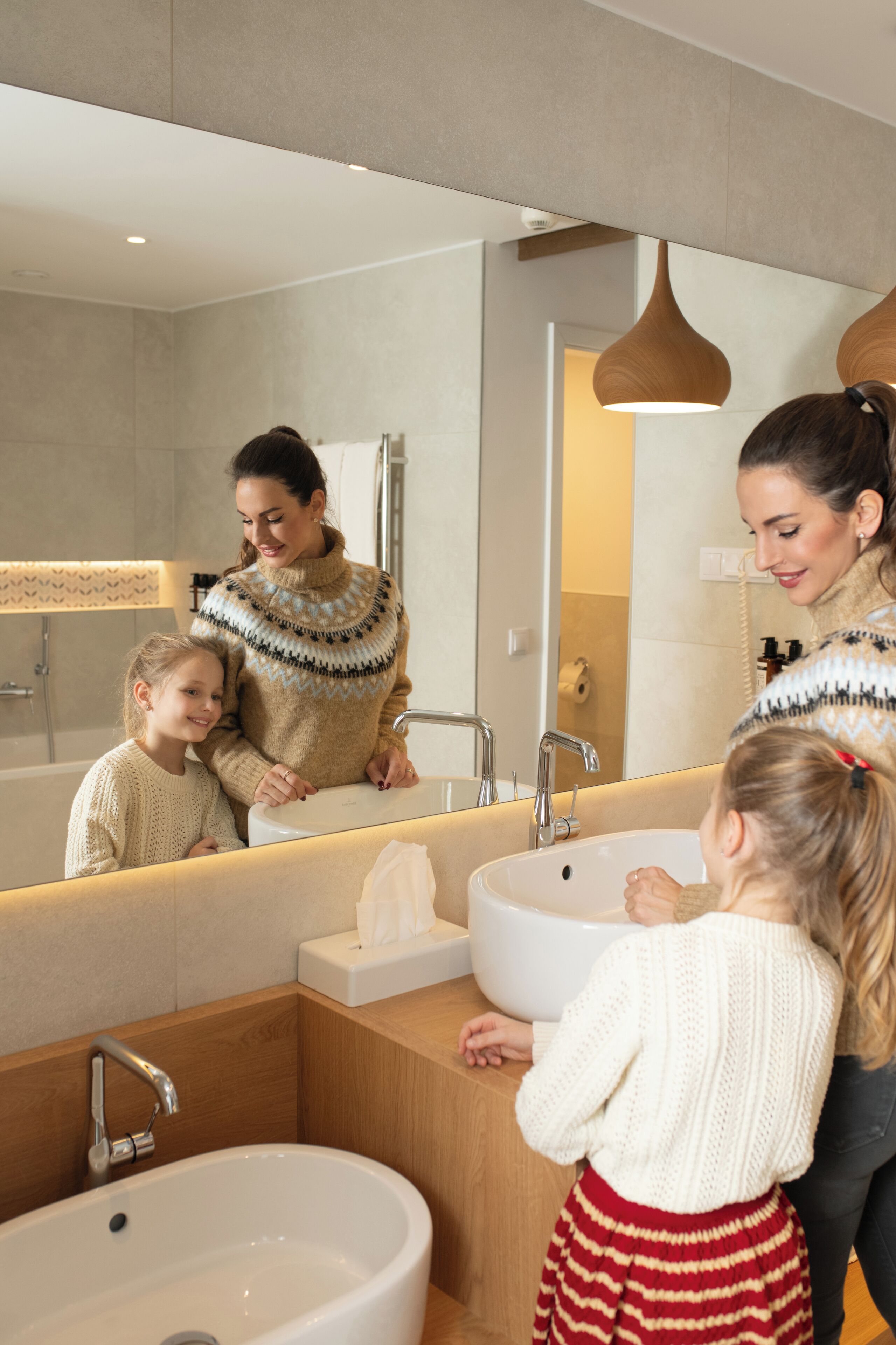 A modern bathroom with a large mirror, a sink, and a bathtub.
