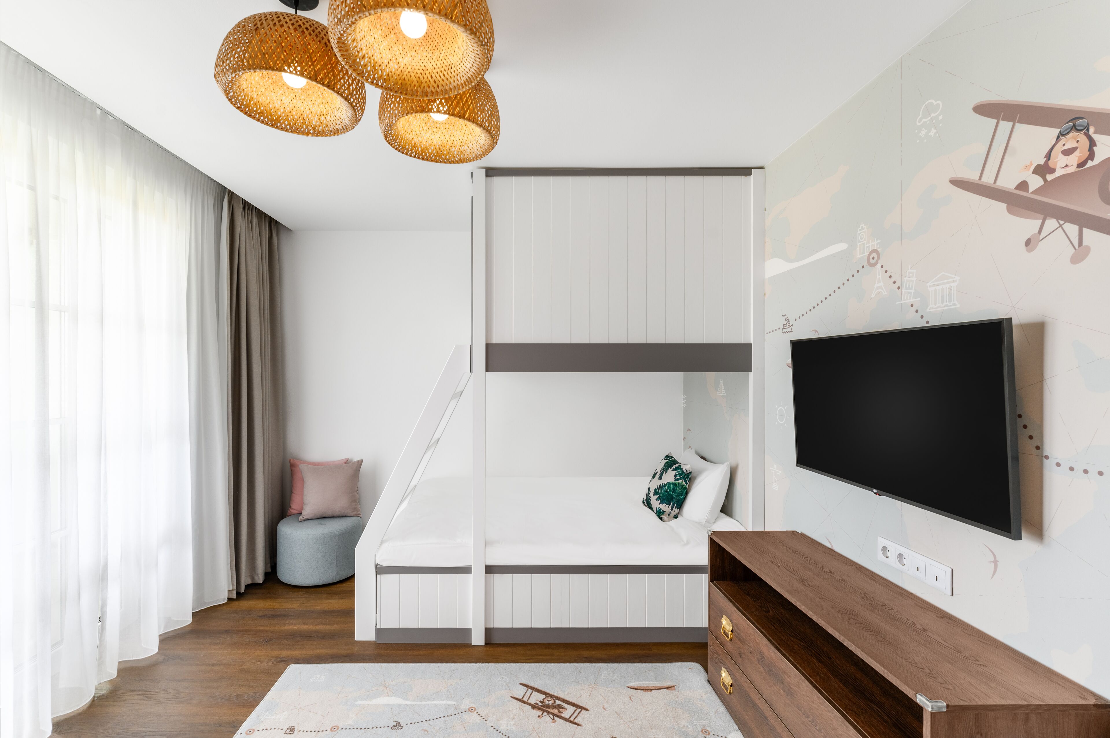 Un dormitorio moderno con una cama litera, un televisor de pantalla plana y un mural decorativo.