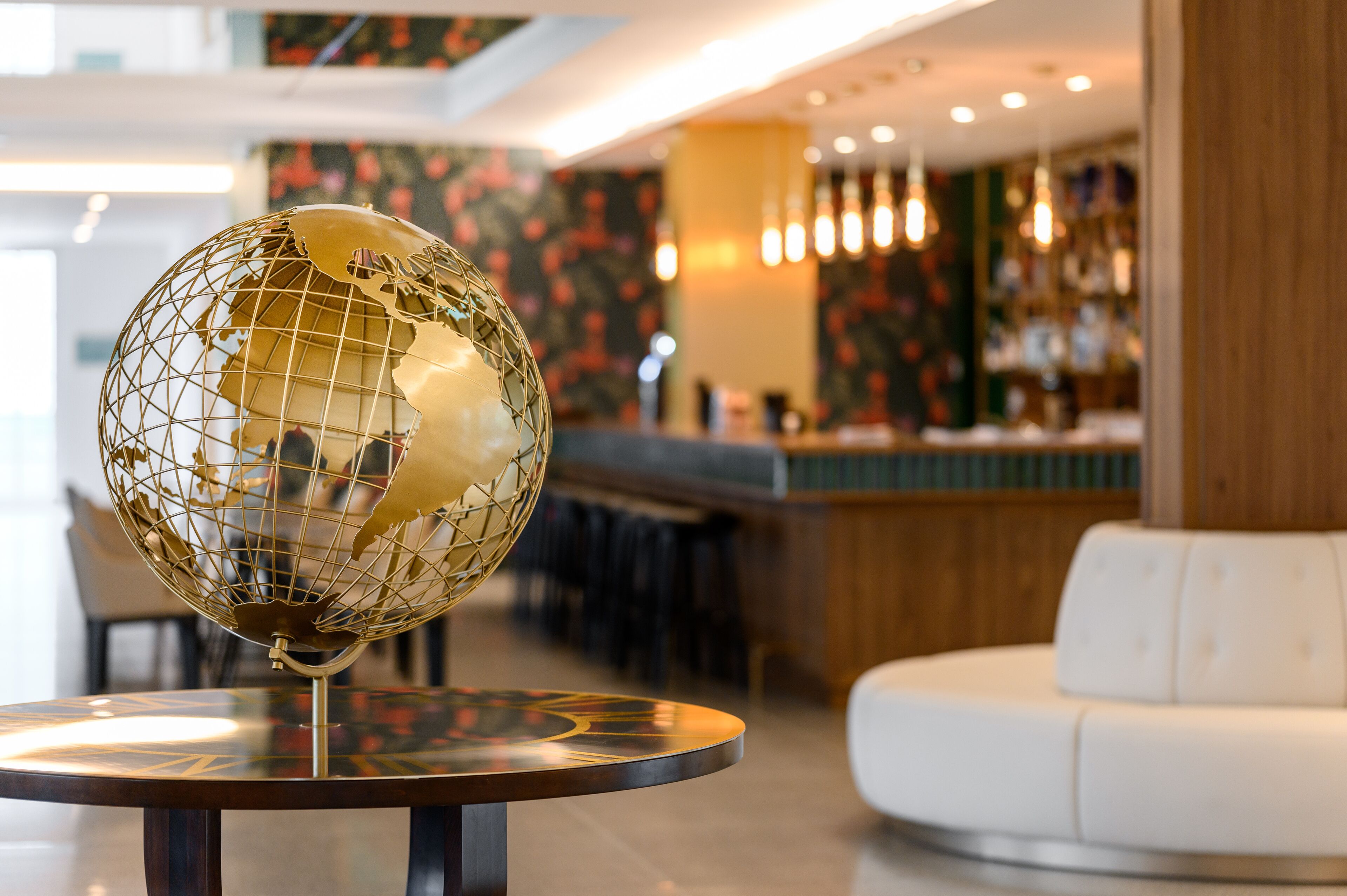 A globe on a table in a modern lobby with a bar and seating area.