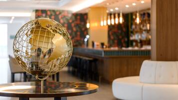 A globe on a table in a modern lobby with a bar and seating area.