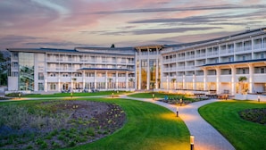 Un hotel de varios pisos con un patio central, zonas de estar al aire libre y un jardín bien cuidado.