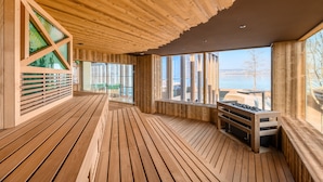 Una terraza de madera con amplios ventanales con vistas al agua.