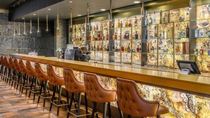 A bar area with a marble wall, a long counter, and multiple stools.