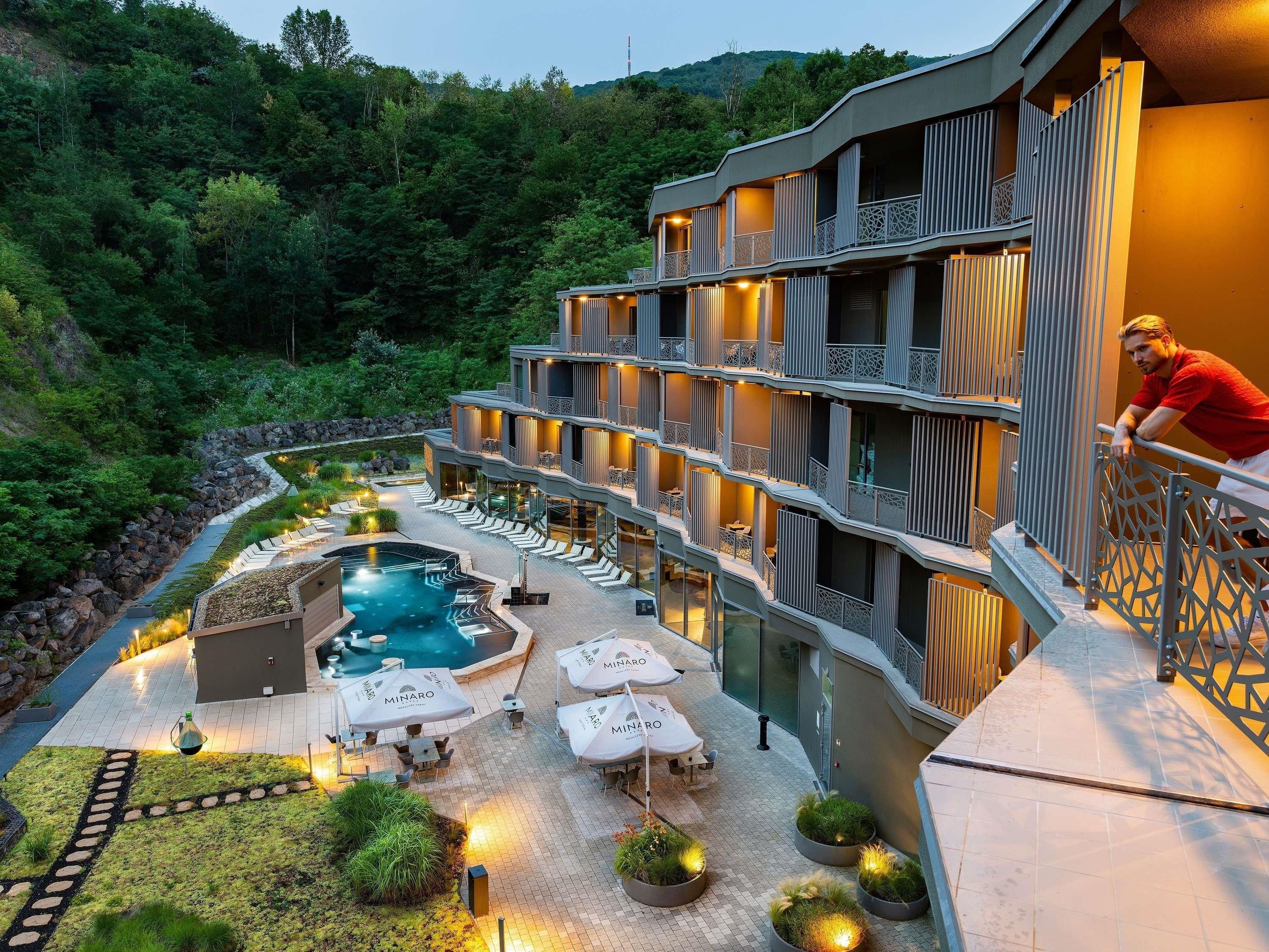 A hotel with a pool, outdoor seating, and a view of the surrounding forest.