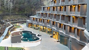A modern hotel with multiple balconies, a swimming pool, and landscaped gardens.