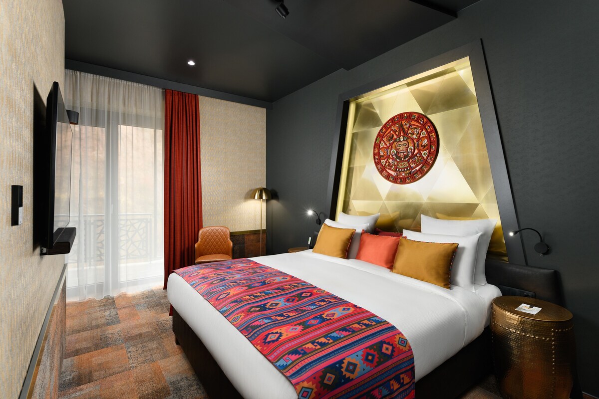 Une chambre d’hôtel moderne avec un grand lit, un élément décoratif mural et une vue sur l’extérieur.