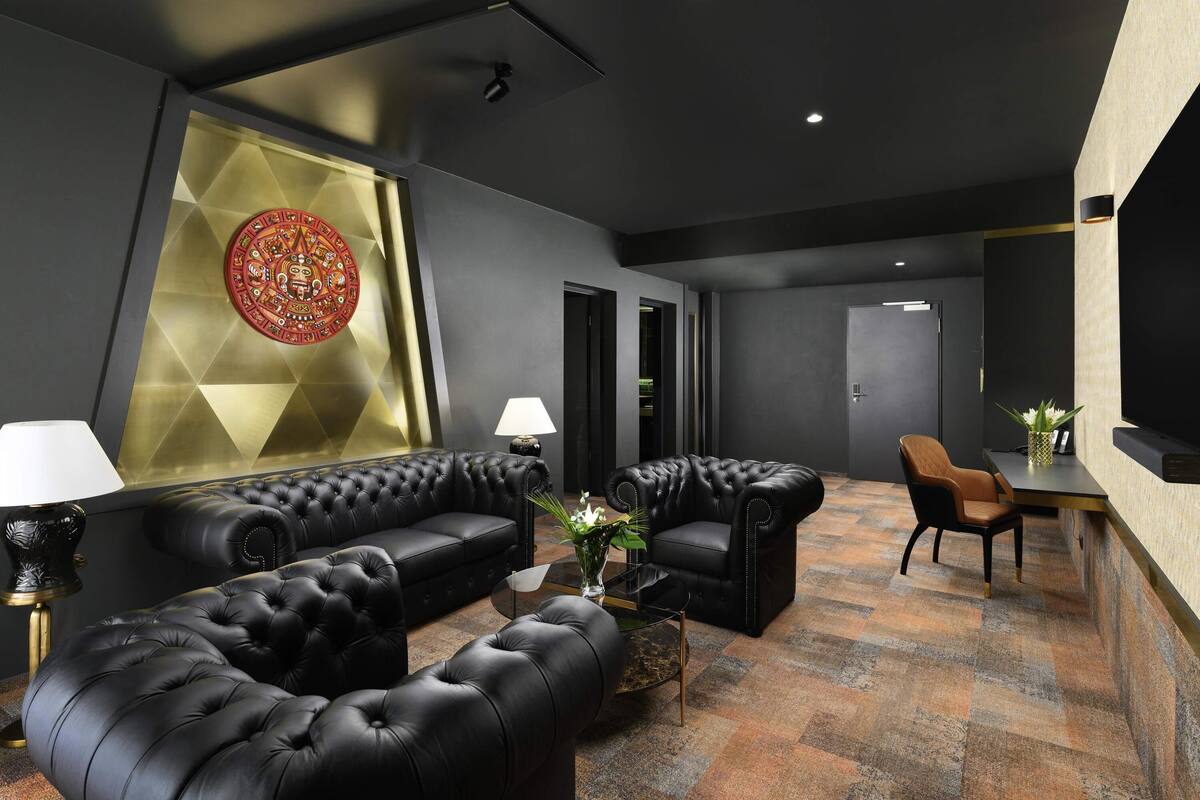A modern lounge area with a black leather sofa, a coffee table, and a decorative wall piece.
