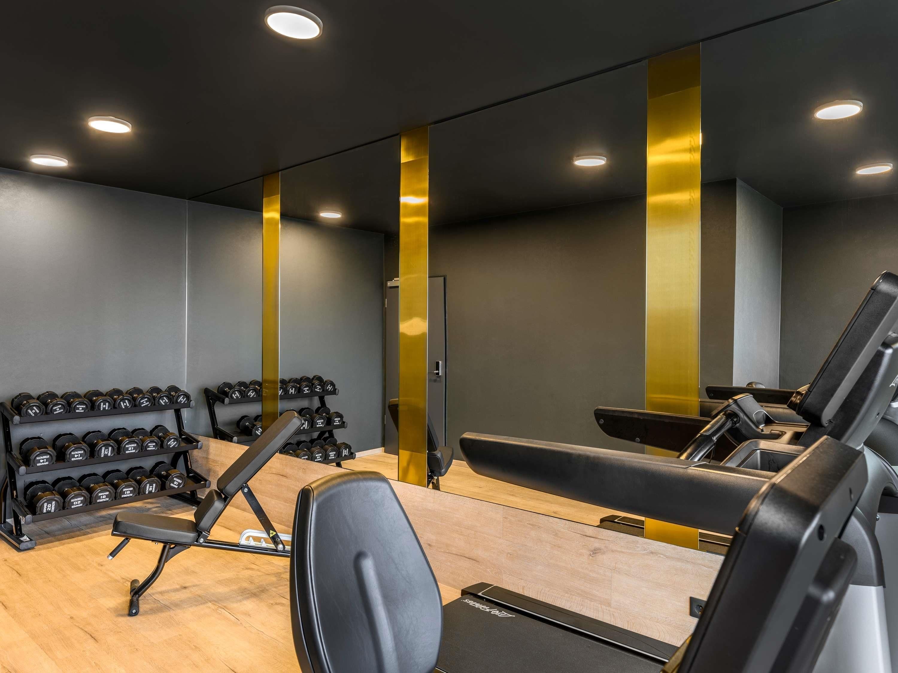 A gym with exercise equipment, including dumbbells, benches, and a treadmill.