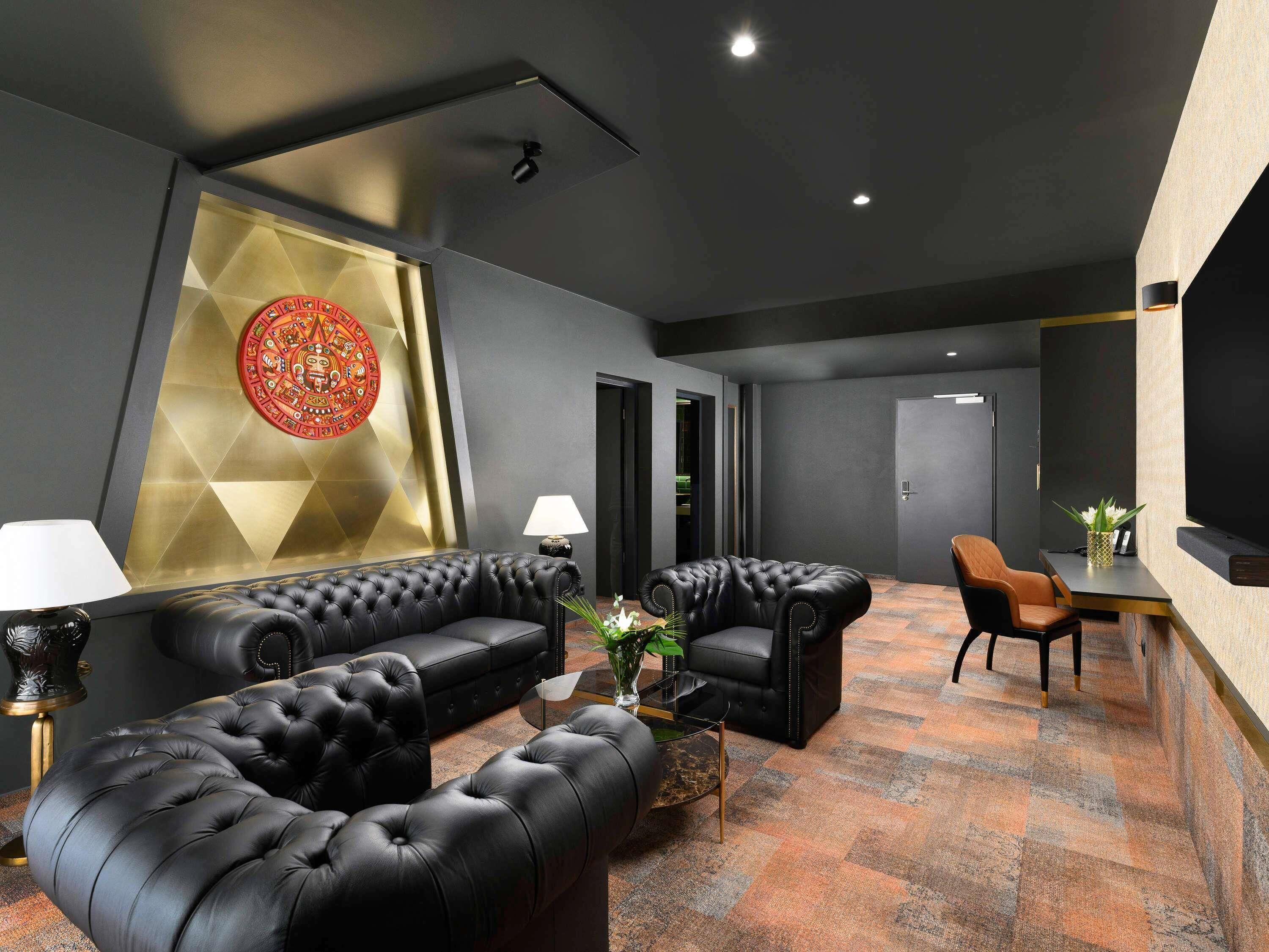 A modern lounge area with a black leather sofa, a coffee table, and a dining table with chairs.
