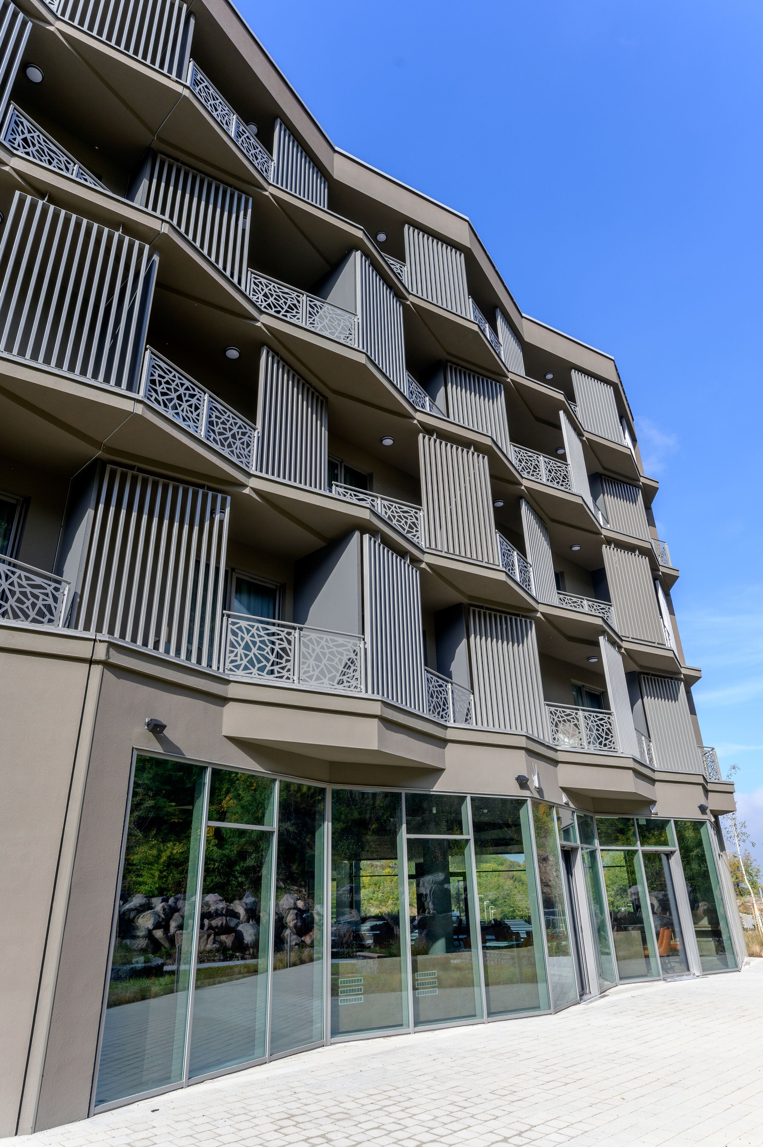 Un edificio moderno con varios balcones, grandes ventanales y techo plano.