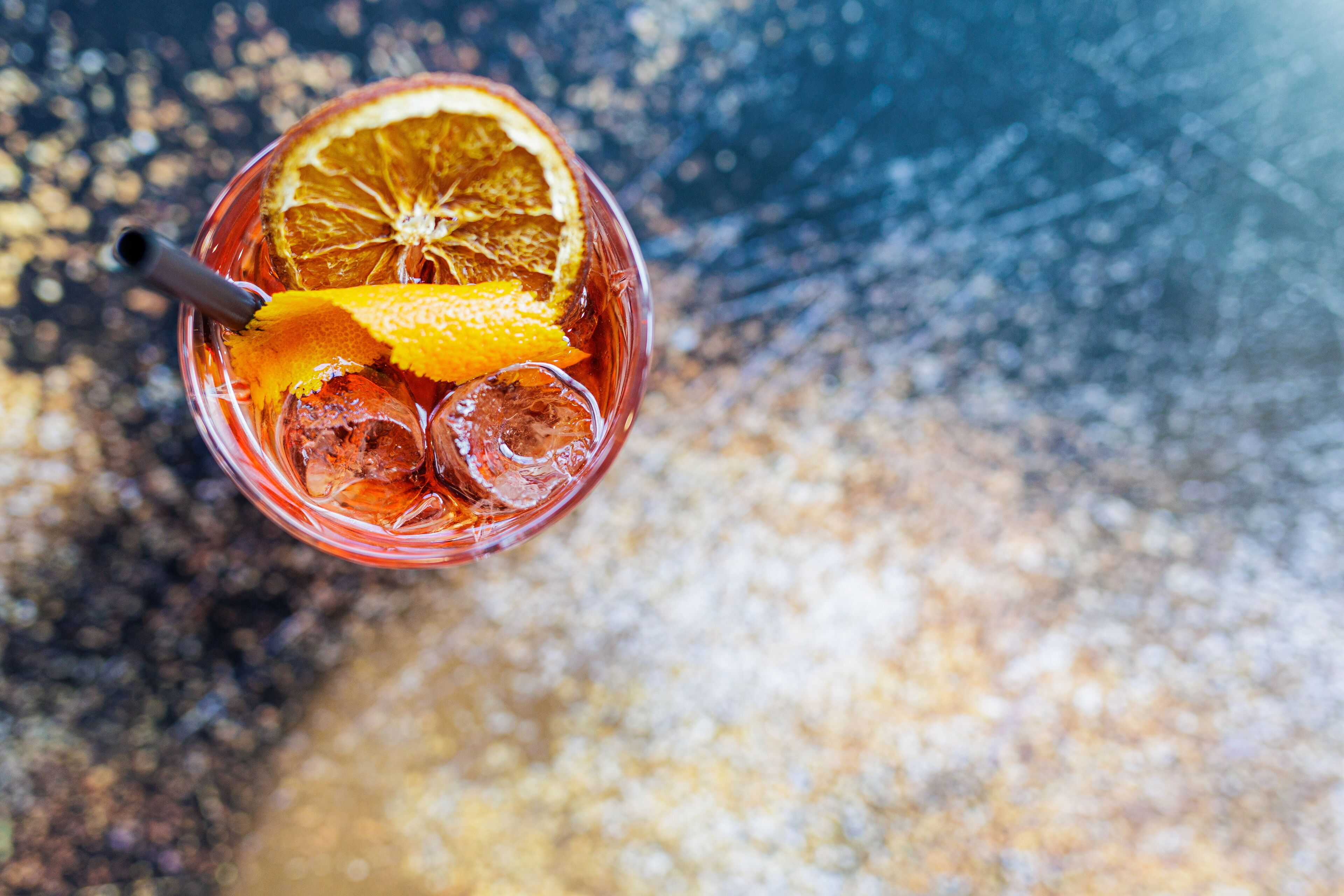 A glass with a slice of orange and ice cubes.