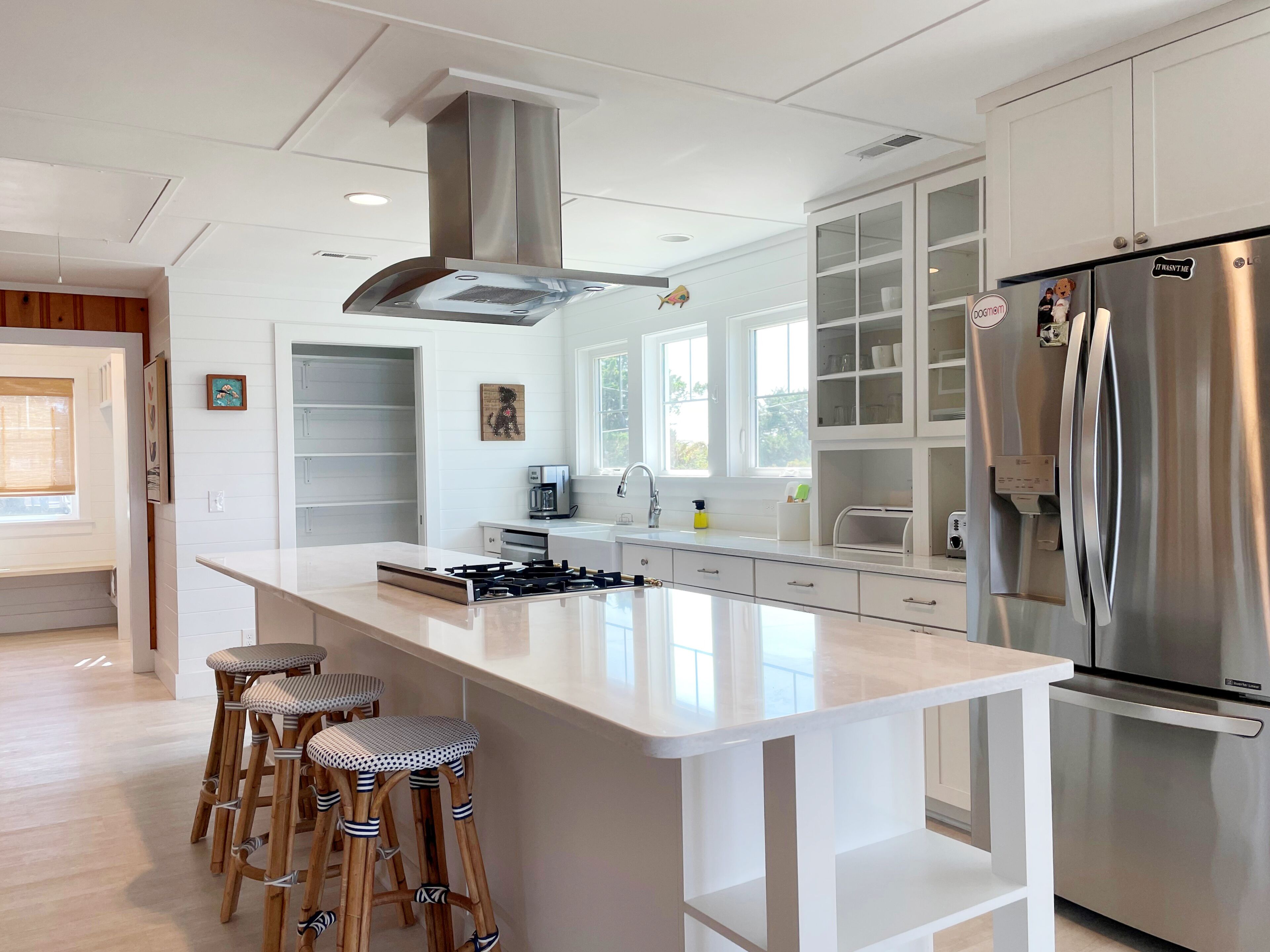 Une cuisine moderne dotée d’un grand îlot central, d’appareils électroménagers en acier inoxydable et d’un coin bar avec des tabourets.