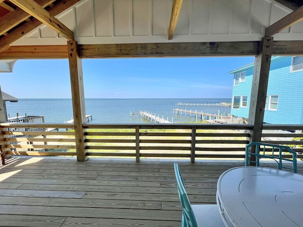 A wooden deck with a view of the ocean and a pier.