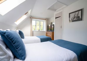 Une chambre avec deux lits, une télévision, une fenêtre et une porte.