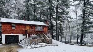Een vakantiehuis van hout met een met sneeuw bedekte dak, een veranda en een garage.
