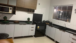 A kitchen with white cabinets, a black stove, a microwave, and a window. - Spacious and cozy country house to welcome your family. (Alumínio)