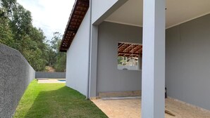 A modern building with a covered patio area, a grassy lawn, and a view of the surrounding landscape. - Spacious and cozy country house to welcome your family. (Alumínio)